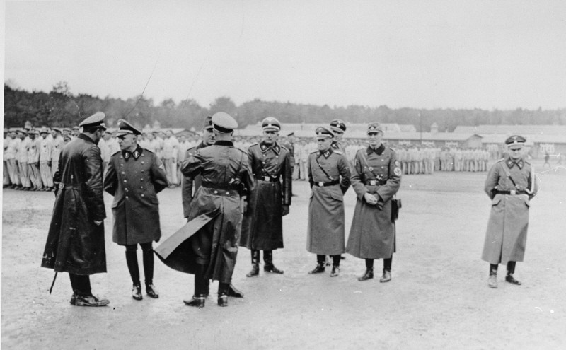 Members of the SS and police speak among themselves during a roll call at the Buchenwald concentration camp. [LCID: 13129]
