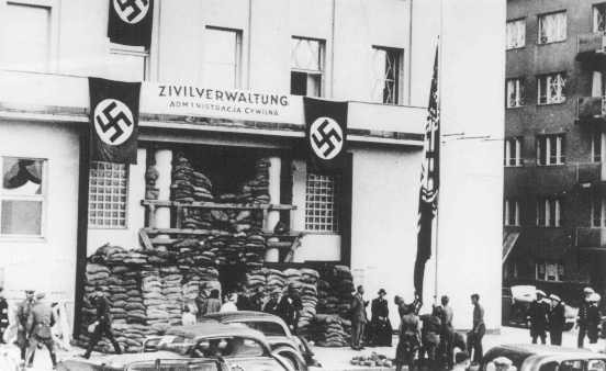 Invading German soldiers raise the Nazi flag in front of the city hall.