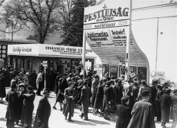 Visitors view the exhibition of the Arrow Cross newspaper, Pesti Ujság, at the International Fair in Budapest. The headline reads:  "For a Hungary without Jews." Budapest, Hungary, approximately 1941-1942.  
The Arrow Cross was Hungary's largest fascist political movement after 1935. In the 1939 parliamentary elections it won over 20% of the vote and had more than 250,000 members. Its ideology was ultra-nationalistic and fiercely antisemitic. The Arrow Cross viewed Jews as an "anti-national" "race" that it held responsible for Communism and finance capitalism. The Arrow Cross demanded that Hungary's Jews be "resettled" outside of Europe.  Karoly Marothy (Marothy Karoly in Hungarian) founded the newspaper, Pesti Ujság, and served in the Hungarian parliament as a member of the Arrow Cross Party.