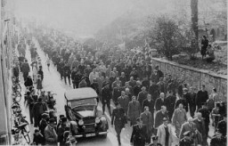 يجبر حراس قوات الأمن الخاصة اليهود الذين تم القبض عليهم خلال ليلة الزجاج المكسور (ليلة الكريستال) على السير عبر مدينة بادن بادن. ألمانيا, 10 نوفمبر 1938.