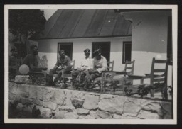 Members of the SS sitting on the terrace of the new officers' dining room (known as the "Kasino") in Sobibor, early summer 1943. From left to right: Hubert Gomerski, Erich Schulze, Gustav Wagner, deputy camp commandant Johann Niemann, and an unidentified man.
This photo comes from a collection donated by the descendants of Johann Niemann. The images in the collection provide never-before-seen views of the killing center, including photos of barracks buildings, workshops, and SS and Ukrainian guards. The album complements and re-enforces the testimonies of the few Jewish survivors of this notorious camp. Niemann was killed during the Sobibor prisoner revolt on October 14, 1943, after which the camp was closed and demolished.
Some of the images (like this one) depict Sobibor personnel laughing, relaxing, and posing for vanity shots all while implementing the mass murder of at least 167,000 innocent Jews.