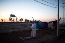A Sunni man from Mosul, Iraq, prays as the sun sets over an internally displaced persons (IDP) camp near Erbil, Iraqi Kurdistan. September 2, 2015.