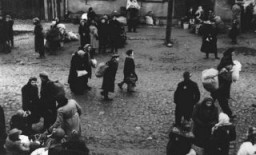 Евреи, несущие узлы с пожитками, перед депортацией из Каунасского гетто, вероятно, в Эстонию. Каунас, Литва, октябрь 1943 года.
Фото: Любезно предоставлено Джорджем Кадишем (Цви-Хиршем Кадушиным).