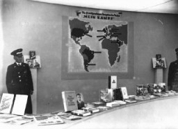 Exibição de publicações nazistas — com os títulos anti-semitas cuidadosamente disfarçados – em exposição durante as Olimpíadas de Berlim. O cartaz na parede mostra os países onde o livro de Hitler, Mein Kampf (Minha Luta) havia sido traduzido para as línguas nativas. Berlim, Alemanha, agosto de 1936.