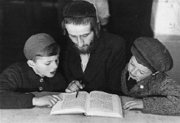 Children learn a religious text from an Orthodox Jewish teacher. Landsberg displaced persons camp, Germany, 1946-1947.