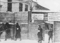 This photograph shows the Rudnicki Street entrance to the Vilna ghetto. The signs on the fence claim there is danger of contagion and prohibit the bringing of food or wood into the ghetto. Photograph taken in 1941–42.