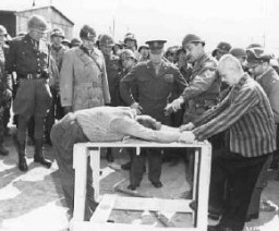 A survivor shows US Generals Eisenhower, Patton, and Bradley how inmates at the Ohrdruf camp were tortured. Ohrdruf, Germany, April 1945.
