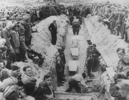 مشيعيون حول خندق ضيق عند وضع ضحايا مذبحة كيلسي في قبر جماعي بعد الجنازة الجماعية. كيلسي, بولندا بعد 4 يوليو 1946.
