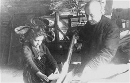 Un hombre judío y una niña judía realizando trabajos forzados en una fábrica del ghetto de Lodz. Lodz, Polonia, fecha incierta.