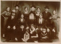 In this 1934 portrait of Norman Salsitz's family, Norman is seated in the front row (at left). In the top row, center, an image of one of Norman's brothers has been pasted into the photograph. This is seen by comparing the size of the brother's face with the others pictured. Pasting in images of family members who could not be present during family portraits was common practice and in some cases the resulting composite images are the only remaining visual records of family groups.