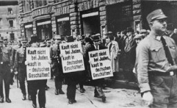 Tres comerciantes judíos son forzados a marchar por una calle de Leipzig atestada de gente mientras llevan carteles que dicen: "No les compren a los judíos. ¡Compren en los negocios de los alemanes!" Leipzig, Alemania, 1935.