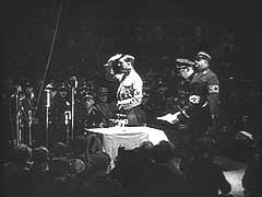 У цій німецькій кінохроніці Гітлер звертається до членів СА та СС у берлінському Палаці спорту, Німеччина. Він дякує їм за підтримку й самопожертву під час боротьби нацистів за владу.