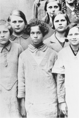 The daughter of a white German woman and a Black French soldier stands among white classmates, Munich, 1936. This image was included as a slide for lectures on genetics, ethnology, and race breeding at the State Academy for Race and Health in Dresden, Germany.  