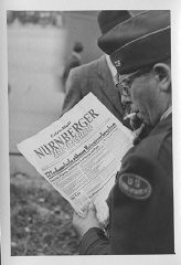 An American correspondent reads a special edition of the Nürnberger newspaper reporting the sentences handed down by the International Military Tribunal. Nuremberg, Germany, October 1, 1946.