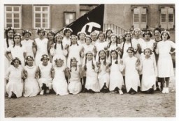Retrato de un grupo de niñas alemanas posando en el exterior de su escuela, frente a una bandera nazi. Entre las niñas retratadas se encuentra Lilli Eckstein, seis meses antes de que fuera expulsada del colegio por ser judía. Heldenbergen, Alemania, 1935.