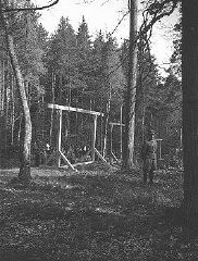 An SS officer standing in front of a newly constructed gallows in the forest near Buchenwald concentration camp. Buchenwald, Germany, April 1942. 