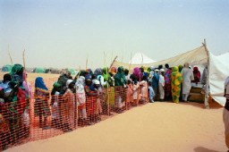 Fila de refugiados em um campo na região leste do Chad para refugiados de Darfur provenientes do país vizinho Sudão. Jerry Fowler, diretor da equipe do Comitê de Consciência do Museu, fez uma visita em maio de 2004 para ouvir, em primeira mão, o relato dos refugiados sobre a violência genocida pela qual passaram e o fato de terem sido empurrados para o deserto.
