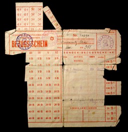 The Nazis made Jewish leaders responsible for the distribution of food supplies and other necessities allotted to ghetto residents. Due to grossly inadequate supplies, the Juedische Selbstverwaltung Theresienstadt (Jewish Administration of Theresienstadt) issued ration cards such as this one. The columns count points allotted for various goods identified by letters of the alphabet. Boxes were removed as residents exchanged points for food or other goods. This view shows the front of the card. Issued in the Theresienstadt ghetto, Czechoslovakia, 1944.
