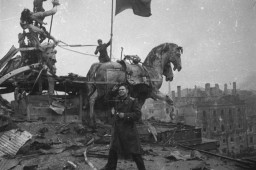 Soviet photographer Yevgeny Khaldei stands on top of the Brandenburg Gate in Berlin where he, along with a few Soviet soldiers, raised the Soviet flag. Berlin, Germany, May 1945.