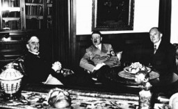 يعقد كل من نيفيل تشامبرلين رئيس الوزراء البريطاني (ناحية اليسار) وأدولف هتلر المستشار الألماني (في الوسط) وإدوارد دالادييه رئيس الوزراء الفرنسي (ناحية اليمين) اجتماعًا في ميونيخ لتحديد مصير تشيكوسلوفاكيا. ألمانيا، 30 سبتمبر 1938.