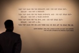 A visitor stands in front of the quotation from Martin Niemöller that is on display in the Permanent Exhibition of the United States Holocaust Memorial Museum. Niemöller was a Lutheran minister and early Nazi supporter who was later imprisoned for opposing Hitler's regime.