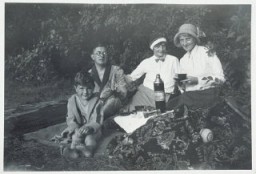 弗里茨•格吕克施泰因（Fritz Glueckstein）（左）与家人野餐。拍摄地点：德国柏林；拍摄时间：1932 年。弗里茨的父亲是犹太人，在一所自由派犹太会堂做礼拜；母亲是基督徒。按照 1935 年纽伦堡法案规定，弗里茨应归为混种（半犹太人）。但由于他父亲是犹太宗教社团成员，弗里茨被归为犹太人。