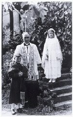 Some Jewish children survived the Holocaust because they were protected by people and institutions of other faiths. Children quickly learned to master the prayers and rituals of their "adopted" religion in order to keep their Jewish identity hidden from even their closest friends. This photograph shows two hidden Jewish children, Beatrix Westheimer and her cousin Henri Hurwitz, with Catholic priest Adelin Vaes, on the occasion of Beatrix's First Communion. Ottignies, Belgium, May 1943.