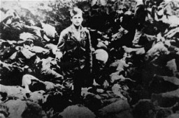 A Ustasa (Croatian fascist) guard stands amid corpses at the Jasenovac concentration camp, Yugoslavia, 1942.