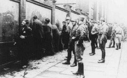 Political opponents of the Nazis, guarded by SA (Storm Troopers), are forced to scrub anti-Hitler slogans off a wall shortly after the Nazi assumption of power. Germany, March 1933.