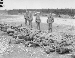Des soldats américains regardent des cadavres de victimes de Kaufering, un sous-camp du réseau de camps de concentration de Dachau. Landsberg-Kaufering, Allemagne, 30 avril 1945.