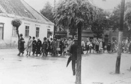 Jewish deportees marching down a main street of Koszeg during the deportation of Hungarian Jews. Koszeg, Hungary, May 1944.