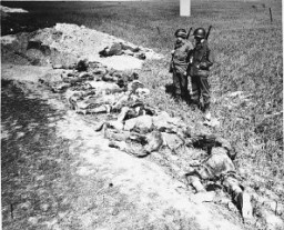 ينظر جنود أمريكان إلى الجثث التي استخرجت من القبور بعد عملية حرق السجناء بمخزن خارج مدينة غاردليغن. ألمانيا, من 14 إلى 18 أبريل 1945.