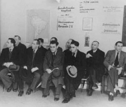 Judíos alemanes, que buscan emigrar, esperan en la oficina de Hilfsverein der Deutschen Juden (Organización de ayuda de judíos alemanes). En la pared, un mapa de Sudamérica y un cartel sobre emigración a Palestina. Berlín, Alemania, 1935.