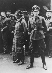 An SS officer stands in front of Jews assembled for deportation. Vienna, Austria, 1941-1942.