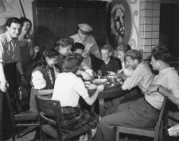 An officer of the United Nations Relief and Rehabilitation Administration (UNRRA) visits with a group of young refugees. Eschwege displaced persons camp, Germany, July 7, 1946.
