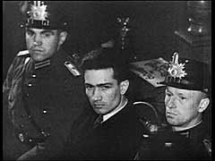 في ليلة 27 فبراير 1933، عامل بناء هولندي عاطل عن العمل يدعى مارينوس فون دير لوب أشعل النار في مبنى الرايخستاج (البرلمان الألماني)، مما تسبب في أضرار خطيرة. اتهم النازيون الشيوعيين وطالبوا بسلطات الطوارئ لسحق كل معارضة. ولتعزيز المطالبات النازية اعتقلت الشرطة أيضا ثلاثة أعضاء بلغاريين من "الشيوعية الدولية"، الذين كانوا في ألمانيا في الوقت، وأيضا شيوعي ألماني رائد. وعلى الرغم من مطالبات النازيين، ومع ذلك، المسؤولية عن الحريق غير واضحة. المحكمة العليا الألمانية حاكمت فقط فون در لوب. برّأت المحكمة المتهمين الآخرين لعدم وجود أدلة كافية على مشاركتهم. تظهر هذه الصورة مشاهد أثناء المحاكمة وبعض الأضرار لمبنى الرايخستاج في برلين.