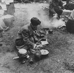 Peu après la libération, des survivants des camps font la cuisine dans un champ. Bergen-Belsen, Allemagne, après le 15 avril 1945.