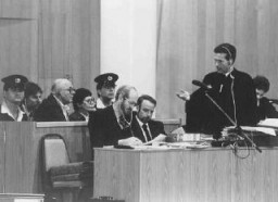 O líder dos advogados de defesa, Mark O'Conner (de pé), faz uma pergunta ao acusado John Demjanjuk durante seu julgamento pelos crimes que cometeu durante a Guerra.  Jerusalem, Israel.  16 de fevereiro de 1987.