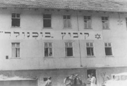 Réfugiés juifs en face du bâtiment du “Kibboutz Buchenwald”, où les Juifs recevaient une formation agricole pour les préparer à la vie en Palestine. Camp de personnes déplacées de Buchenwald, Allemagne, vers août 1946.