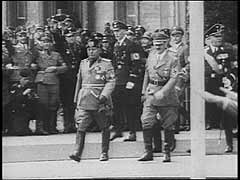 У 1936 році Німеччина та Італія підписали угоду про військовий союз. Обидві держави утворили так звану Вісь Берлін-Рим. На цих кадрах зображений державний візит італійського фашистського лідера Беніто Муссоліні до Німеччини у вересні 1937 року. Він зустрівся з Гітлером у Мюнхені, і обидва лідери також відвідали інші частини Німеччини. Під час державного візиту Муссоліні взяв участь у військовому параді у Берліні, столиці Німеччини. Хоча обидва диктатори заявили про своє прагнення до миру, в 1939 році Німеччина почне Другу світову війну. Тоді Італія вступить у війну як союзник Німеччини проти Великобританії та Франції.