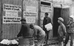 آوارگان یهودی مشغول نصب اعلامیه هایی هستند که در آن خواستار مهاجرت به فلسطین شده اند. اردوگاه آوارگان فلدافینگ، آلمان، پس از ماه مه 1945.
