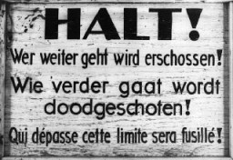 لافتة خارج محتشد بريندونك الانتقالي تحذر أن المارة غير المسموح بهم سيتم إطلاق النار عليهم. بريندونك، بلجيكا، في الفترة من 1940-1944.
