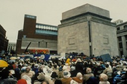 A large crowd fills Eisenhower Plaza during the dedication ceremony of the United States Holocaust Memorial Museum. Flags of the liberating divisions form the backdrop to the opening ceremony. Washington, DC, April 22, 1993.