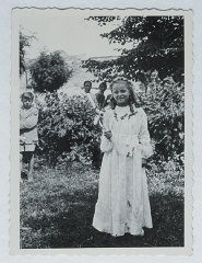 Selma Schwarzwald poses outside while wearing her first communion dress. Selma lived in hiding as a Polish Catholic during the war. Busko-Zdroj, Poland, 1945.
