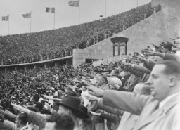 All'interno dello stadio olimpico, durante l'undicesima edizione dei Giochi, il pubblico tedesco saluta Adolf Hitler. Berlino, Germania, agosto 1936.