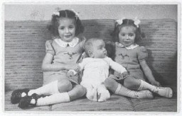 Três irmãos: Eva, Alfred, e Leane Munzer.  O bebê Alfred conseguiu sobreviver por haver sido escondido; suas irmãzinhas foram descobertas e levadas para serem assassinadas pelos nazistas em Auschwitz.