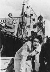 Leni Riefenstahl, with Adolf Hitler in the background, directs the shooting of a film about the Reich Party Day. Here she is shooting a segment called "Day of the Reich Work Service." Nuremberg, Germany, 1936.