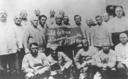A foglyok megalázása: A Szociáldemokrata Párt (SPD) tagjai egy táblát tartanak, amelyen a következő olvasható: „Osztálytudatos személy vagyok, pártvezető/SPD/pártvezető.” Dachaui koncentrációs tábor, Németország, 1933 és 1936 között.