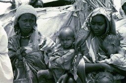 Foto tirada na parte leste do Chade, mostrando mães e filhos em um campo para refugiados oriundos da região de Darfur, no vizinho Sudão. Jerry Fowler, diretor da equipe do Comitê de Consciência do Museu, em maio de 2004 fez uma visita àquela região para ouvir o relato pessoal dos darfurianos sobre a violência genocida pela qual passaram, bem como sobre como foram  escorraçados para o interior do deserto.