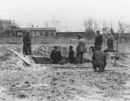Prisioneiros efetuando trabalho escravo no campo de concentração de Oranienburg sob a vigilância de soldados das SS e da polícia de guarda do campo. Oranienburg, Alemanha.  Foto de 1934.